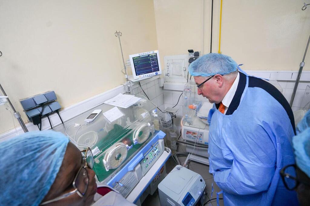 The UNFPA deputy executive director, Andrew Saberton, examines an incubator in a maternity ward in Chad, dressed in medical attire.