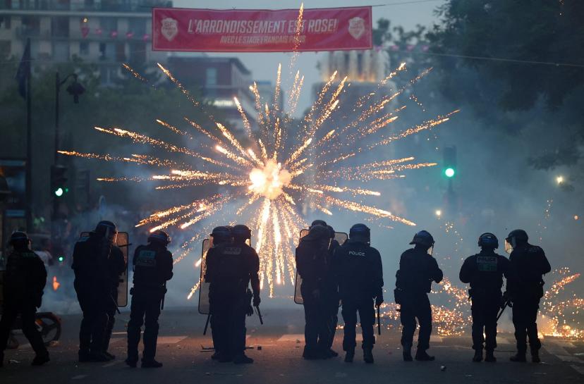 Fireworks erupting in front of CRS units on Champs-Élysées after PSG's Champions League victory