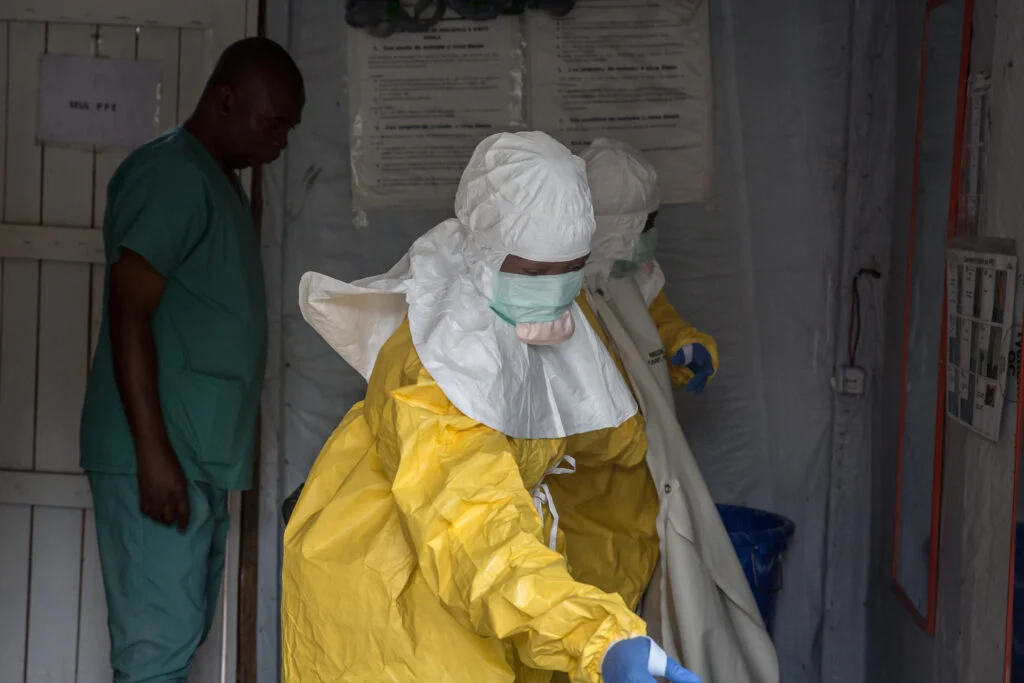 Health workers in protective gear handling medical supplies during an Ebola outbreak response in the Democratic Republic of Congo