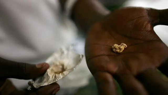 A hand holding a gold nugget